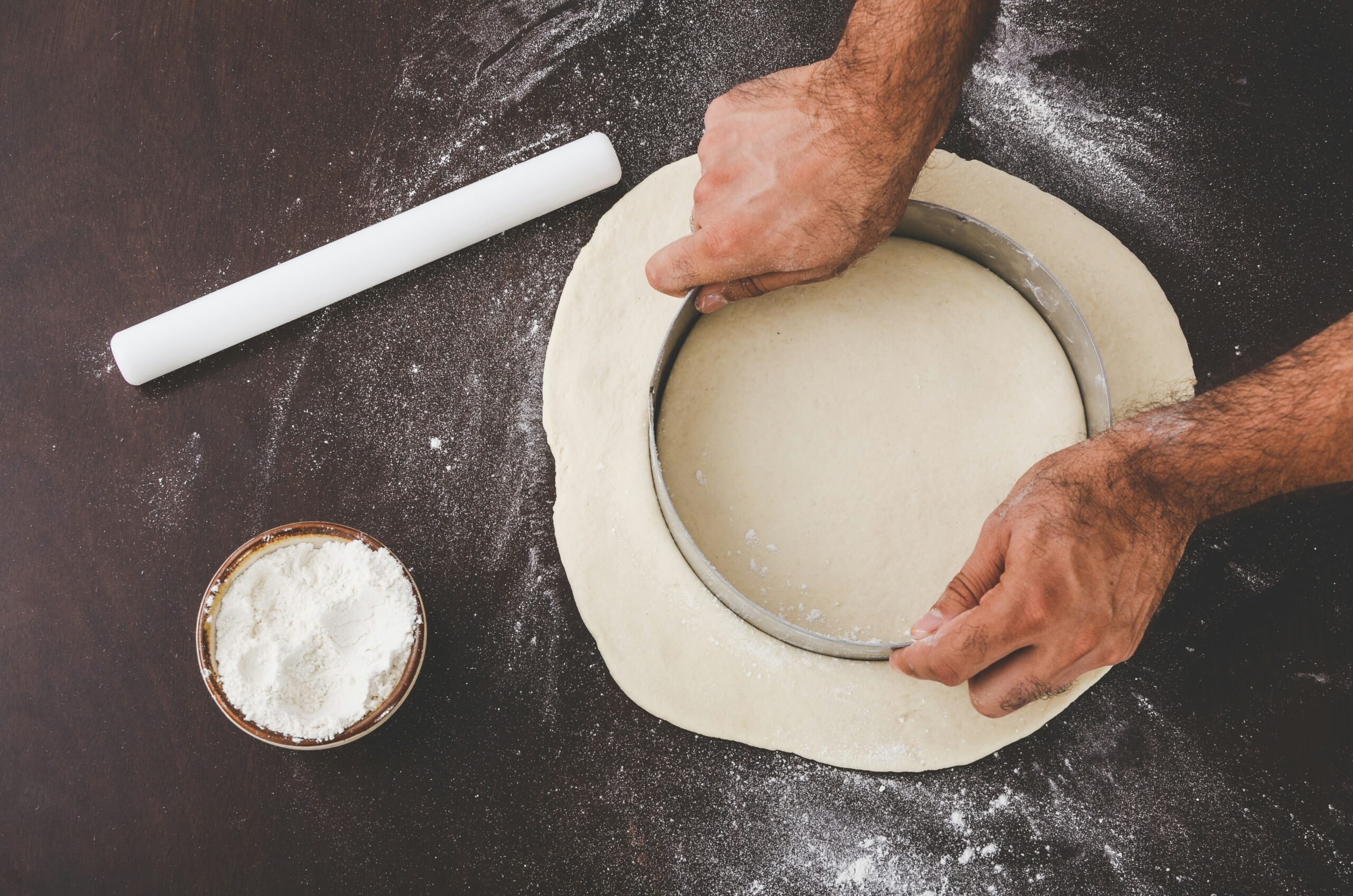 person cutting dough with round cutter